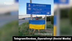 Военнослужащий ВСУ с украинским флагом у дорожного указателя в Курской области России, 13 августа 2024 года