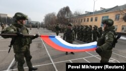 Российские военные складывают флаг во время церемонии начала вывода войск ОДКБ из Казахстана